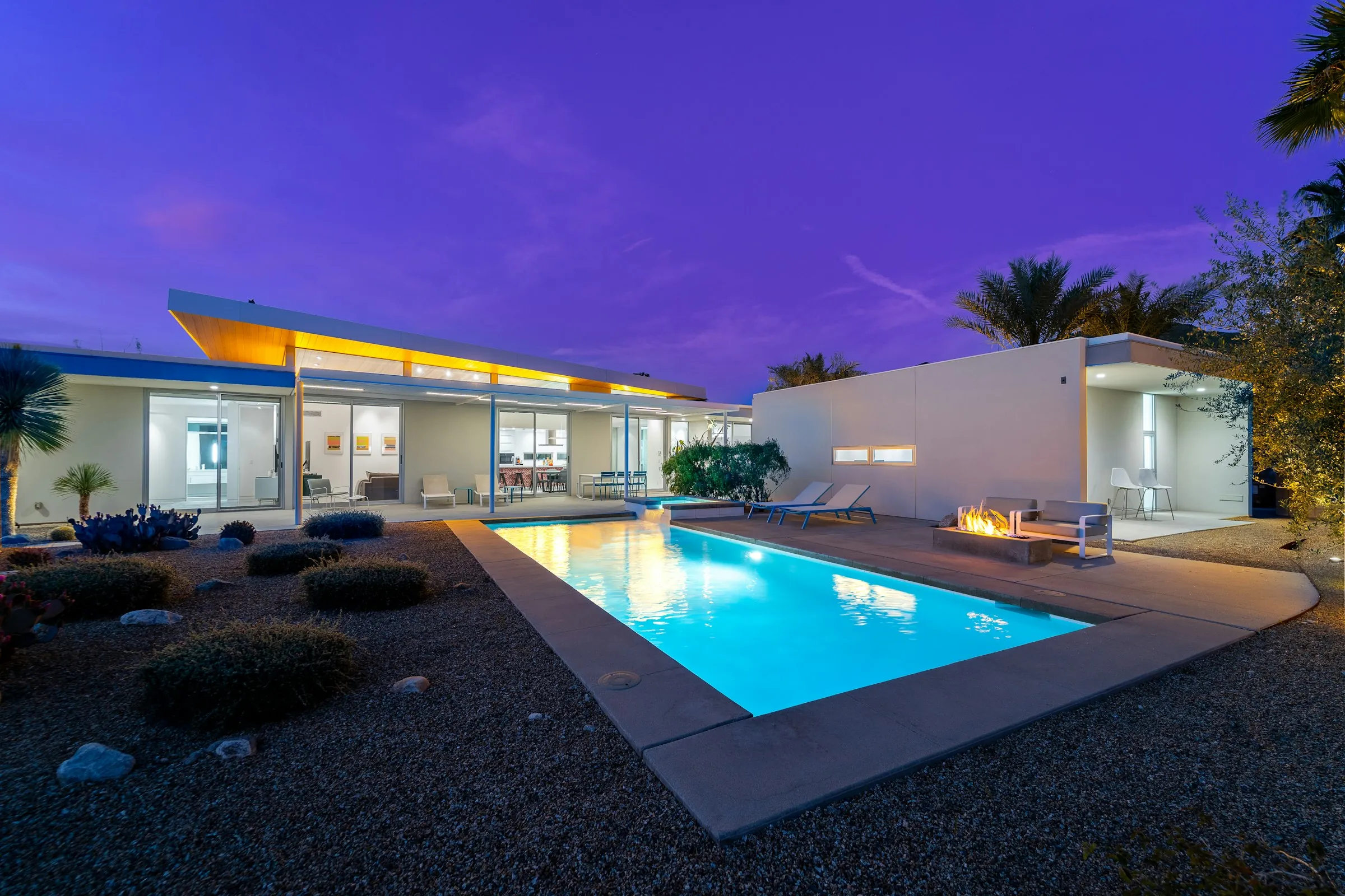 Modern residence with an illuminated pool at dusk